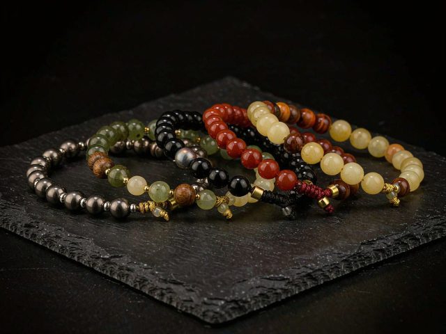 Five beaded bracelets arranged on black slate