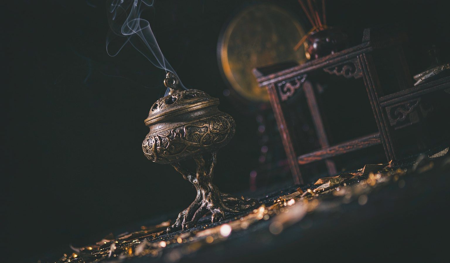 A dark altar with a brass incense burner and gold light