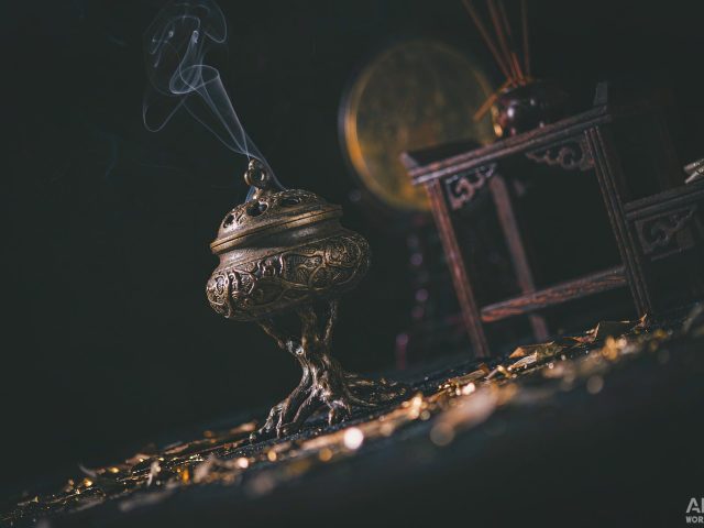 A dark altar with a brass incense burner and gold light
