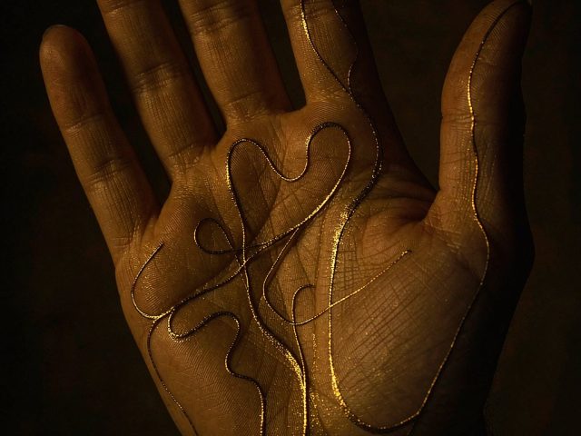An open palm with fine golden lines traced over it