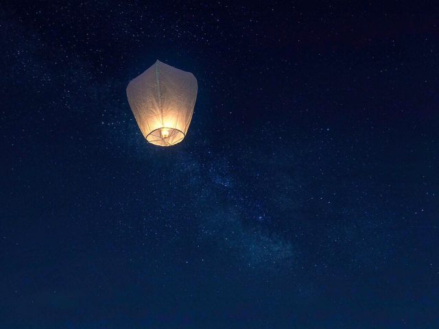A paper sky lantern glowing at dusk